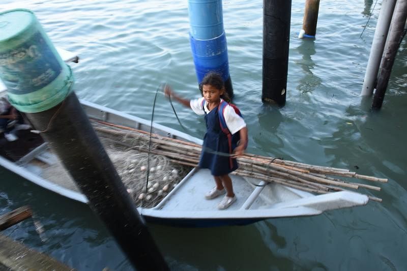 原住民小女孩在渔行渡头，协助父亲，为小舟系上绳索。
