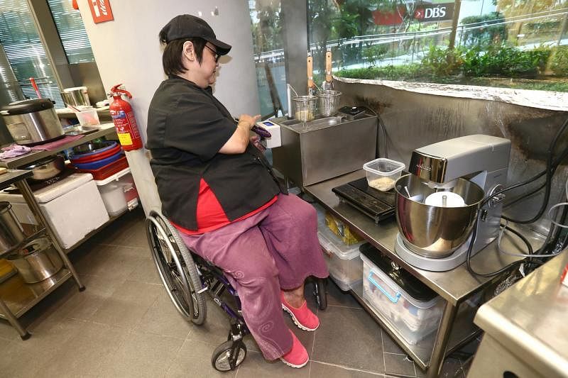 厨师何俐莲坐在轮椅上用自动煮面机烹煮意大利面。