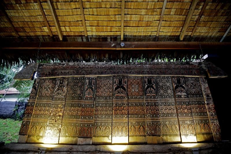 茅草屋墙上挂着一排峇厘岛朴实细腻的老木雕。