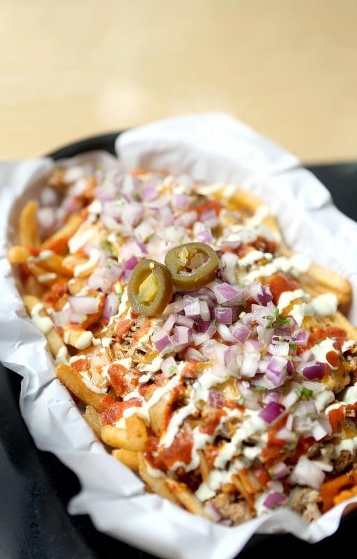 Vatos Urban Tacos的招牌“猪肉泡菜芝士薯条”（The Kimchi Carnitas Fries）。