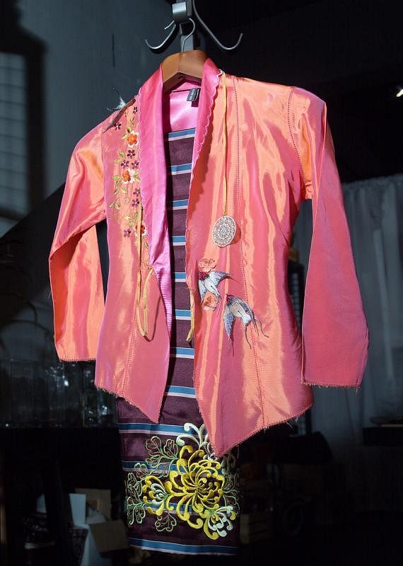 杨福来的新设计风格：橘色丝质卡峇雅绣了几只立体的燕子，纱笼车花蟹爪菊精致生动。