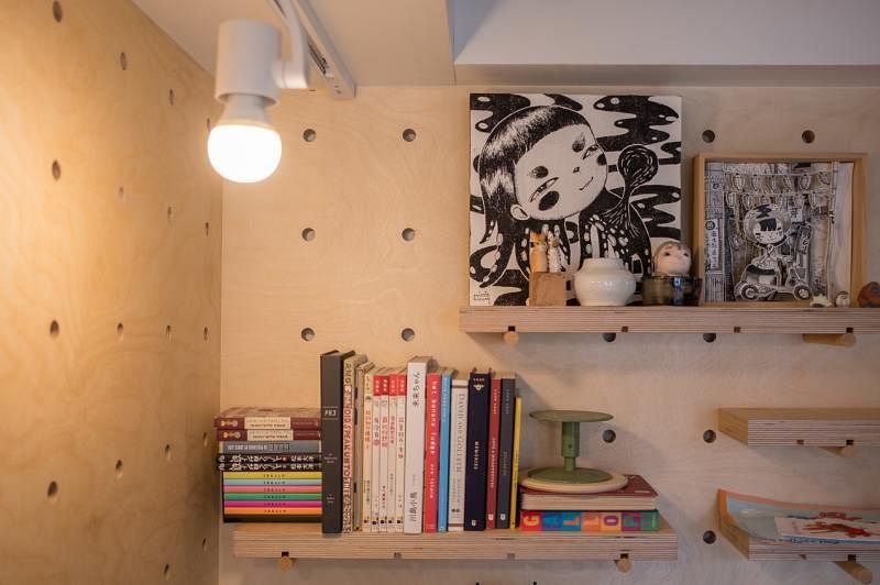 设计师在胶合板墙上打洞，让夫妇可以根据自己的需求添加新书架，摆设他们的日文创意书籍和画作。