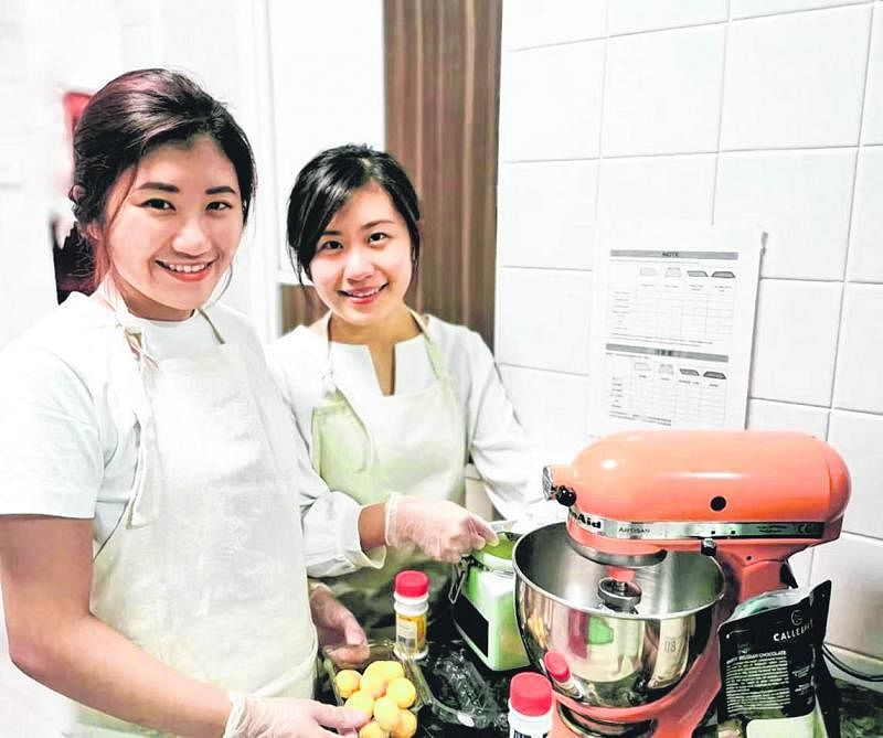 何芸绮（左）和妹妹何佳颖在厨房尝试制作新的蛋糕。（受访者提供）