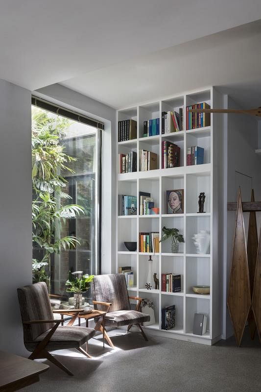设计师为屋主在客厅一角打造高挑书橱，隔出一隅宁静的读书空间。