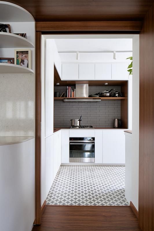 设计师用深色木框将干厨房和饭厅圈成一区，白色壁橱柜用弧形收边，一拐即通往湿厨房。