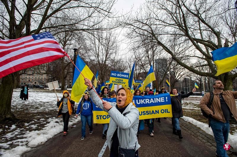 一名乌克兰妇女挥舞美国国旗，带领民众在波士顿和平示威，呼吁对俄罗斯石油实施禁运。（法新社）