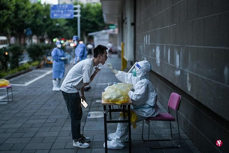 上海防疫工作人员周二（7月5日）在静安区为一名男子做冠病核酸检测。（法新社）
