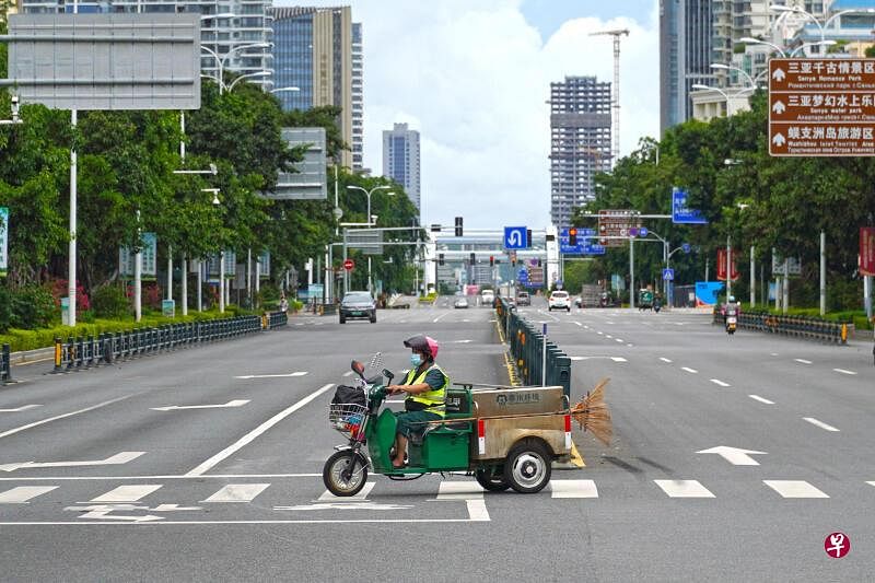 中国海南省三亚市一名清洁工人，8月6日驾驶摩托车路过当地一条空旷的街道。（路透社）