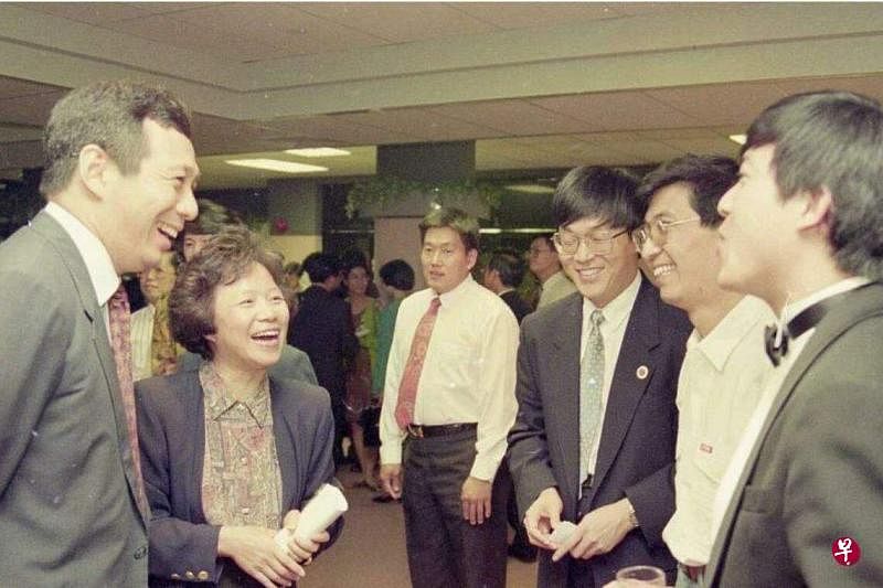 新加坡总理李显龙与中国政协主席王沪宁见面时展示了一张老照片。照片中，时任副总理的李显龙准将（左一）在1993年新加坡国际大专辩论会茶话会上与参赛团队交流。右二为当年在复旦大学国际政治系任职的王沪宁，左二为当年辩论赛节目监制朱亮亮，右一是剑桥大学辩论队辩手、英语系博士生孙学军，右三是已故的复旦大学哲学系教授俞吾金。右四是比赛赞助商大华食品的第三代接班人白毅柏。（《联合早报》档案照）