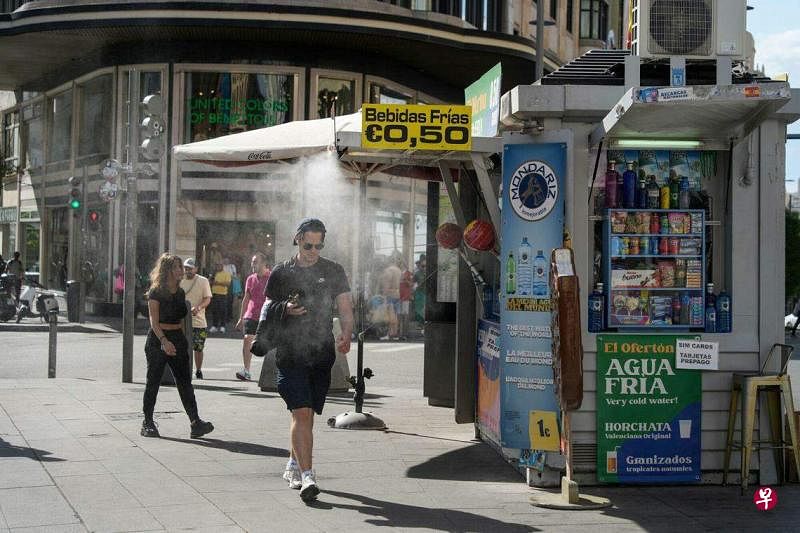 西班牙今年的热浪提前到来，部分地区本周气温将达到40摄氏度。图为西班牙首都马德里高温天的街景，行人走到降温喷雾下解暑。