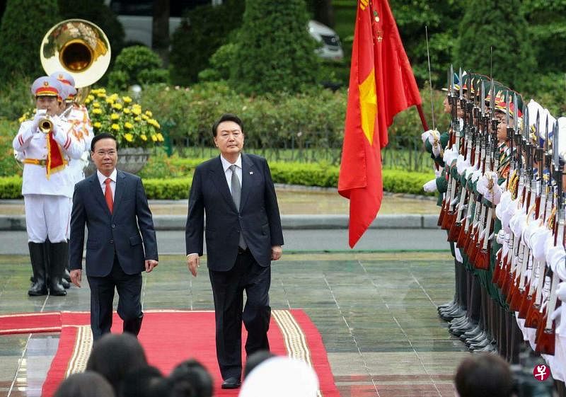 韩国总统尹锡悦（穿大衣者右）6月23日在越南国家主席武文赏的陪同下，在河内总统府检阅仪仗队。（路透社）