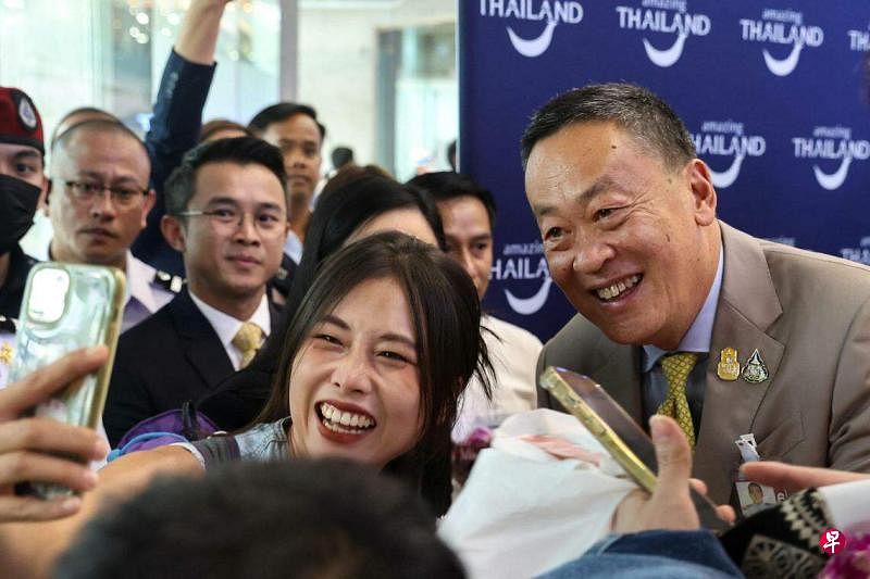9月25日，泰国实施免签证入境政策当天，泰国首相社德他到曼谷国际机场迎接首批抵境的中国游客，与一些游客合影。（路透社）