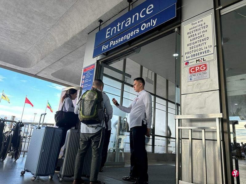 菲律宾空中交通服务部门接到飞机可能爆炸的警告。图为乘客星期五（10月6日）在马尼拉大都会帕赛市尼诺·阿基诺国际机场一号航站楼入口处，向安检人员出示登机牌。（路透社）