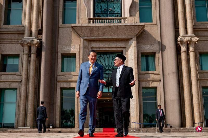 10月11日，马来西亚首相及财政部长安华（右）在总理办公室前与泰国新任首相社德他（左）交谈。（路透社）