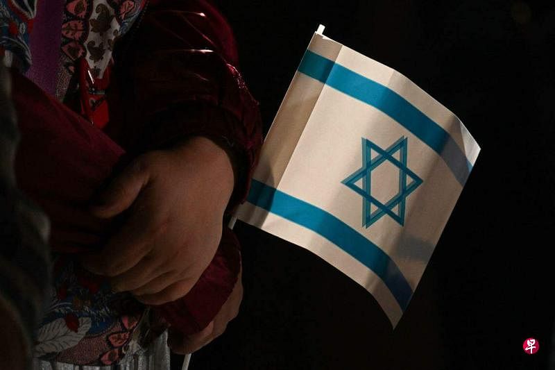 德国慕尼黑和上巴伐利亚以色列社区在奥赫尔雅各布犹太教堂举行“与以色列一起哀悼”的团结集会，一名女孩手握一枚以色列小国旗。（法新社）