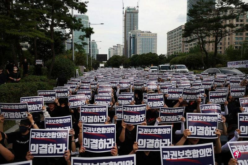 韩国教师9月4日在首尔举行示威，为一名不堪家长霸凌的24岁女教师轻生表达抗议。示威教师手举一张“投票赞成保护教师权利协议”的海报。（路透社）