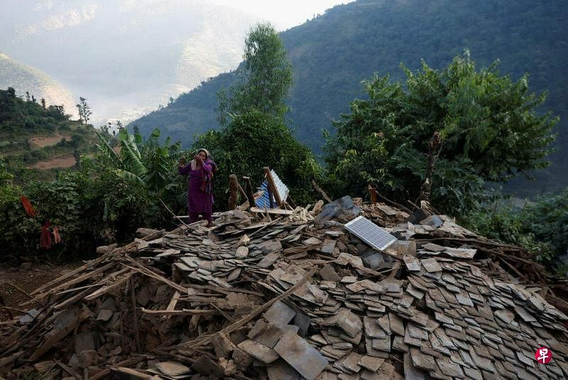 尼泊尔地震将老百姓的土房震塌后，无家可归的幸存者只能在露天过夜。图为一妇女站在已成废墟的“房顶”上。（路透社）