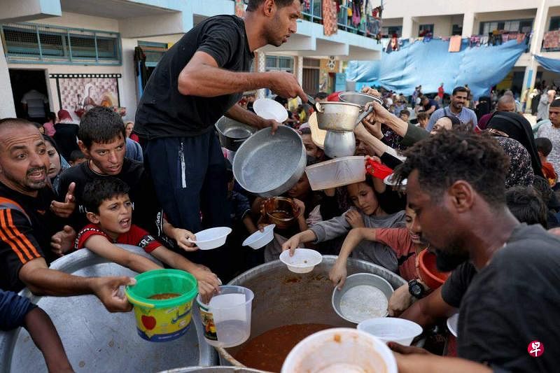 加沙地带被以军围堵后严重缺水缺粮。图为当地的巴勒斯坦人向联合国的志愿工作者领取食物。（法新社）