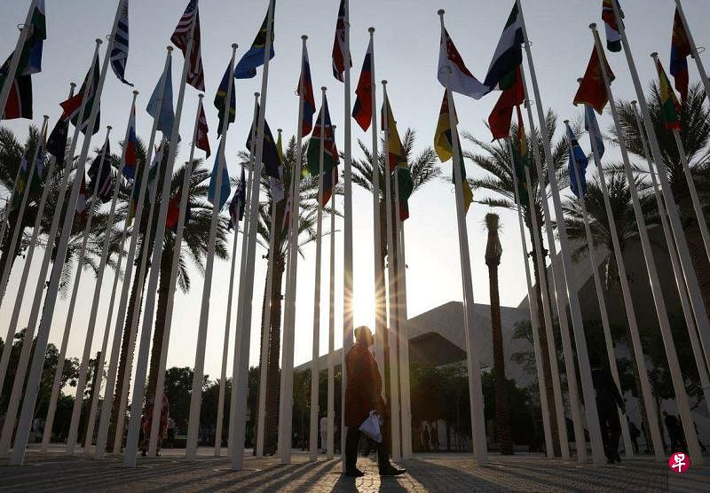 11月30日，《联合国气候变化框架公约》第28次缔约方大会（COP28）在阿拉伯联合酋长国展开，一名男子走过挂满约150国旗帜的广场。（路透社）