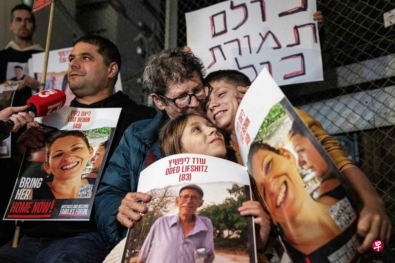 以色列和哈马斯的暂时停火协议持续了一周，双方互换了多批人质和囚犯。11月28日晚上，一名获释的以色列老人（戴眼镜）与家属在以色列国防部大楼外参与示威。（法新社）
