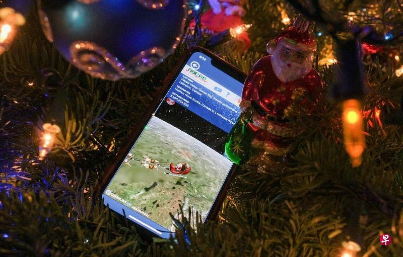 挂在洛杉矶一棵圣诞树上的一台手机屏幕，显示着北美空防司令部的圣诞老人追踪器页面。（法新社）