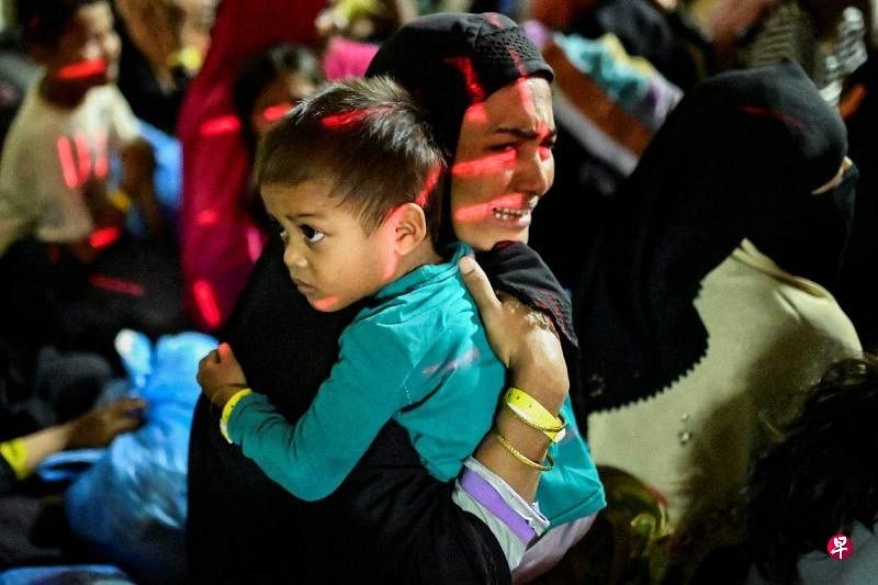 印尼数百名大学生星期三（12月27日）闯入亚齐一个罗兴亚难民收容中心，要求将他们驱逐出境。一名罗兴亚妇女抱紧孩子，在被迫转移到另一个难民中心时，难掩不安。（路透社）