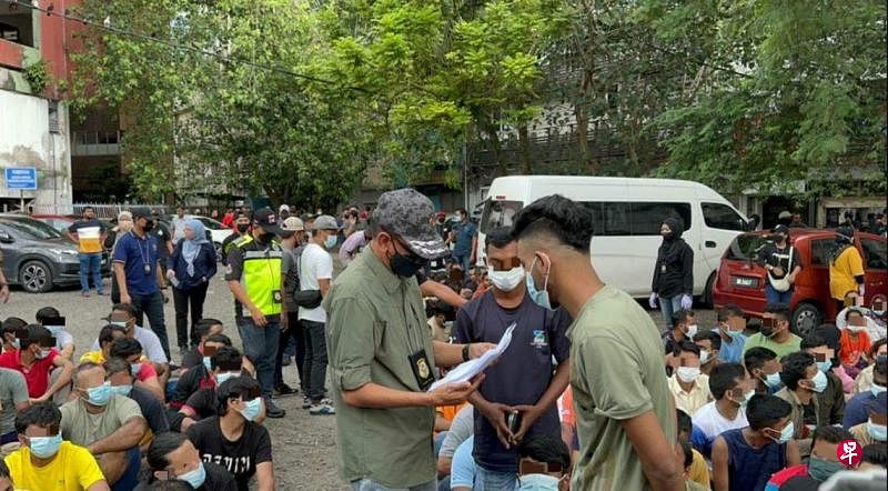马国多个执法单位星期一下午在吉隆坡素有“小印度”之称的十五碑取缔非法移民。图为移民局负责取缔行动的副总监杰菲里（左）检查两名被捕者的文件。（星洲日报）