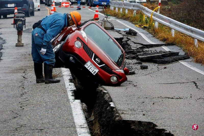 在石川县穴水町附近，一条公路裂开，一辆汽车被卡在裂缝里动弹不得。（路透社）