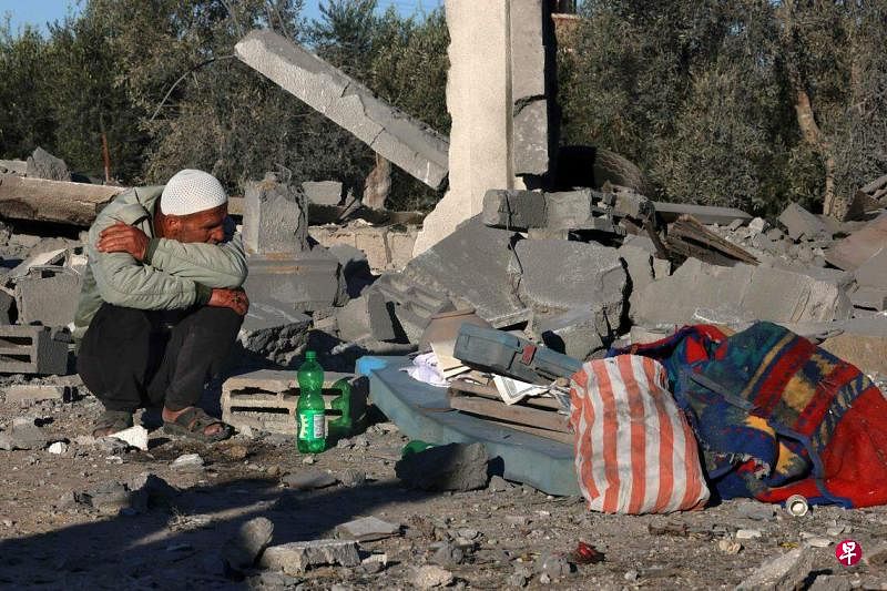 1月13日，以色列轰炸加沙地带南部的拉法后，一名男子坐在建筑物的废墟中。（法新社）