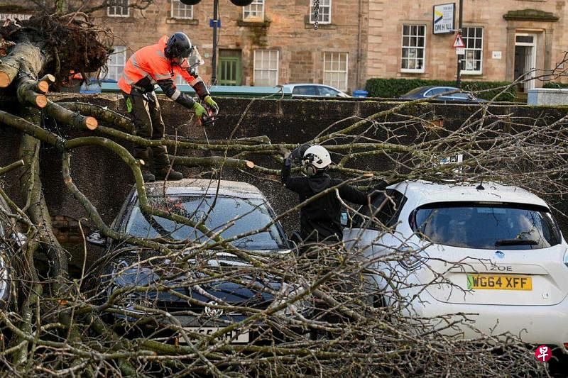 风暴伊莎导致英国部分地区遭遇多年来未遇的强风，图为西洛锡安，树枝修剪工忙着清理折断的树枝。（路透社）