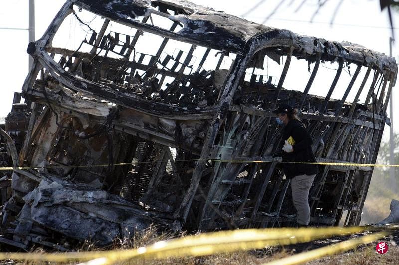 1月30日，锡那罗亚州检方工作人员在车祸现场展开调查。照片显示，出事的双层巴士已经严重烧毁。（法新社）