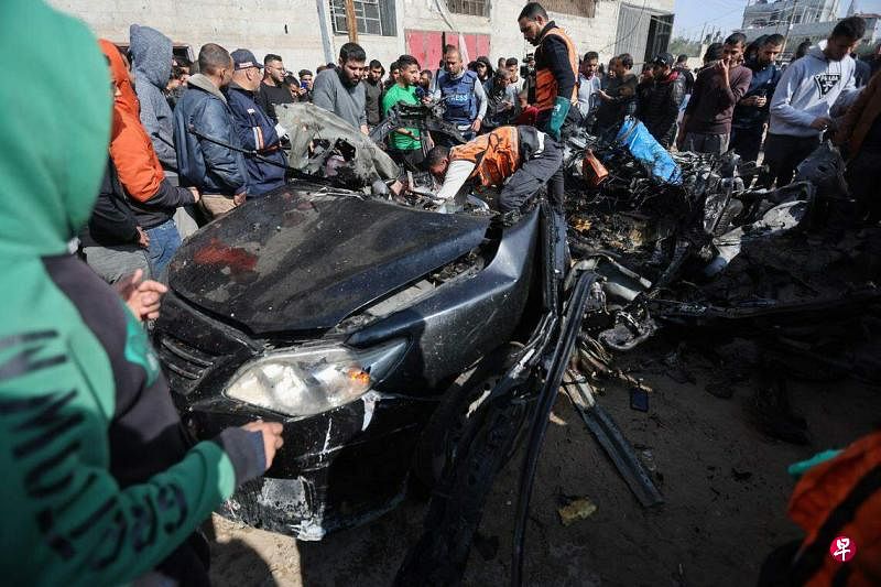 2月10日，在加沙南部拉法市，巴勒斯坦民众检查一辆被以色列空袭击中的汽车。（路透社）