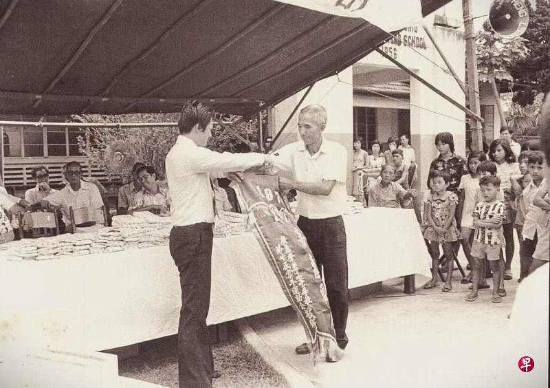 1972年碧山亭学校运动会上，郭明校长（右）从碧山亭当届理事长罗荣基手里接过锦旗。（作者提供）