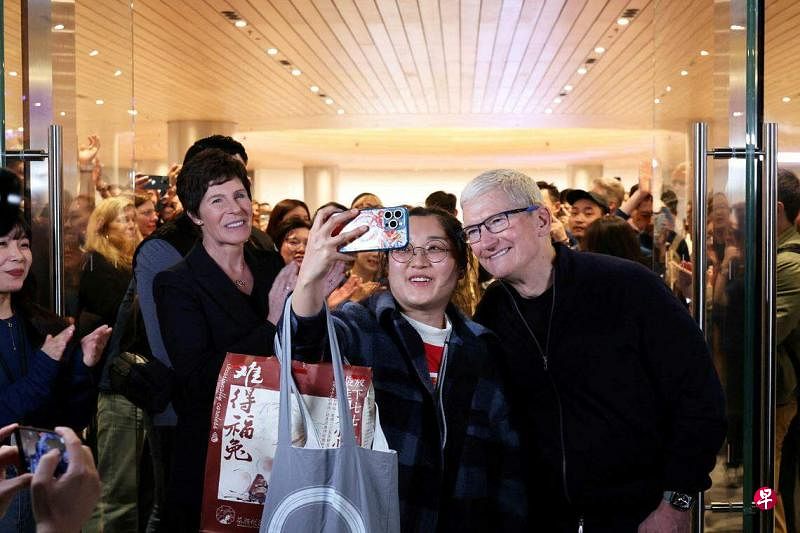 苹果首席执行官库克3月21日参加苹果上海静安零售店开业仪式，与到场顾客自拍。（路透社）