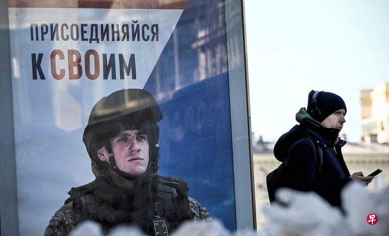 俄罗斯国防部星期三（4月3日）称，自上个月莫斯科市郊音乐厅发生致命袭击以来，应征入伍的人大幅增加。3月12日，在俄罗斯莫斯科西部，一名男子经过呼吁应征入伍的海报。（法新社）