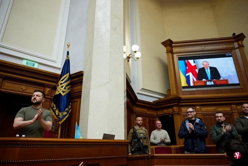英国首相约翰逊通过视频链接向乌克兰议会发表讲话，他称乌克兰将击败俄罗斯。乌克兰总统泽连斯基（左）自战争开始以来第一次出席议会。（路透社）

